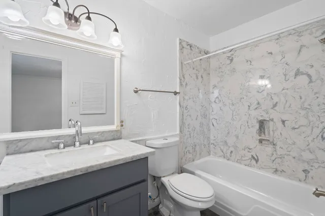 a bathroom with a granite countertop sink a toilet and shower