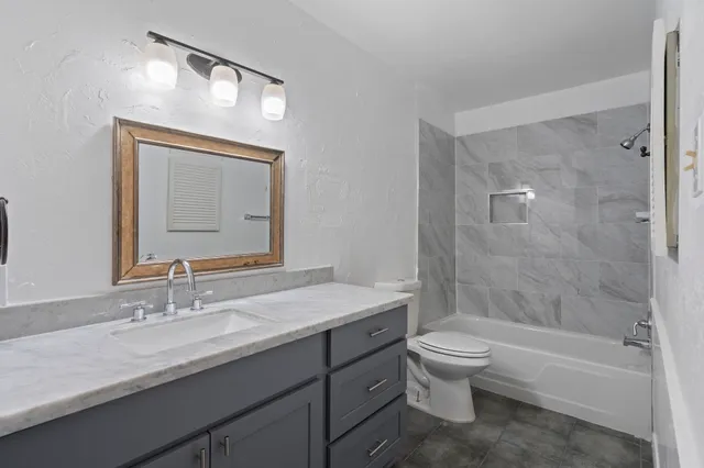 a bathroom with a granite countertop sink a toilet and bathtub