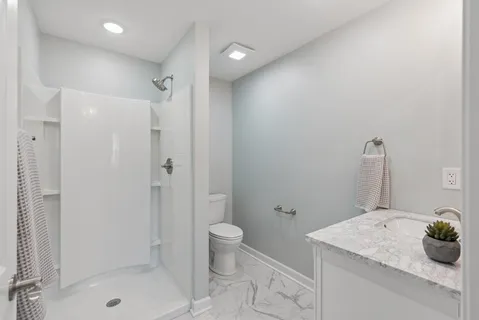 a bathroom with a granite countertop sink a toilet and shower