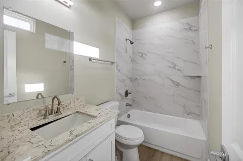 a bathroom with a granite countertop sink a toilet and bathtub
