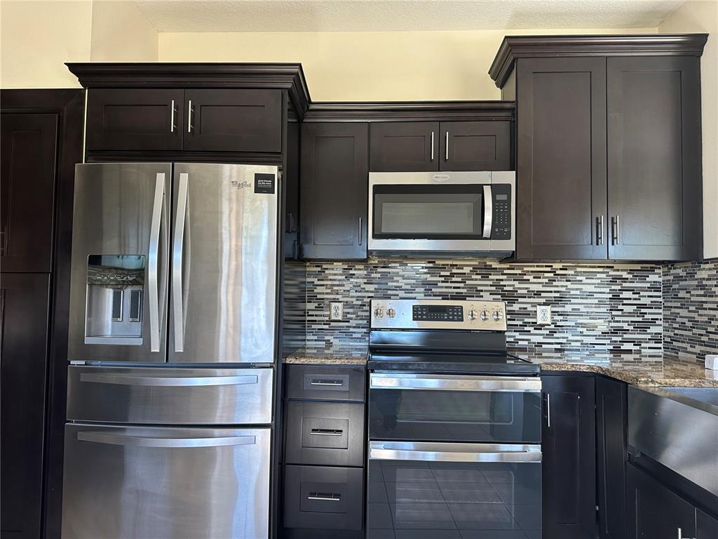 4150 Vanern Way Kissimmee, FL 34746 - Photo 9 of 51 a kitchen with granite countertop stainless steel appliances and wooden cabinets