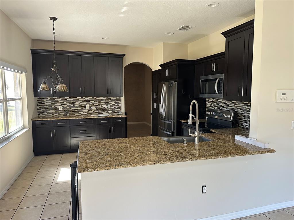 4150 Vanern Way Kissimmee, FL 34746 - Photo 10 of 51 a kitchen with stainless steel appliances granite countertop a sink and a refrigerator