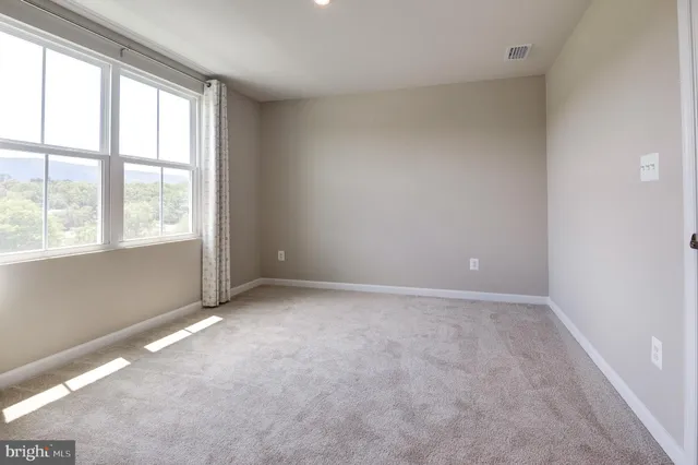 a view of empty room with wooden floor and windows