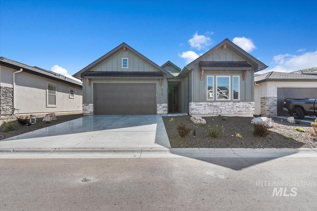 Craftsman house featuring stone siding, board and batten siding, driveway, and an attached garage