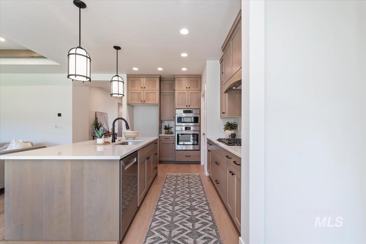 2242 East Rodeo Street Kuna, ID 83634 - Photo 12 of 37 Kitchen with pendant lighting, recessed lighting, appliances with stainless steel finishes, light wood finished floors, and a center island with sink