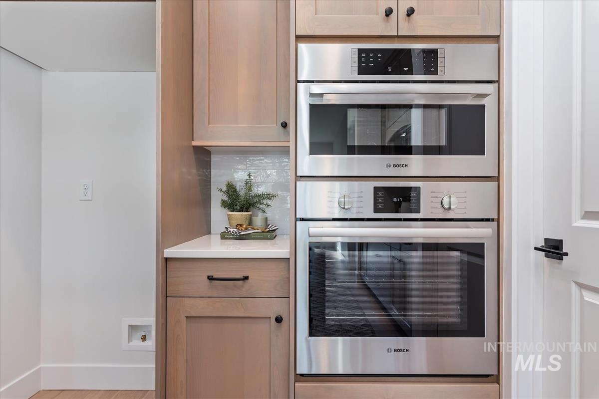 2242 East Rodeo Street Kuna, ID 83634 - Photo 15 of 37 Kitchen with stainless steel double oven, backsplash, light stone countertops, and light wood finished floors