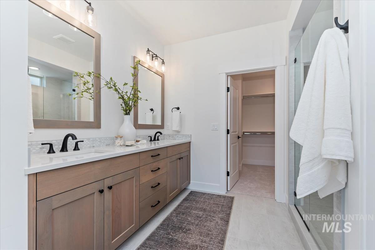 2242 East Rodeo Street Kuna, ID 83634 - Photo 27 of 37 Bathroom with double vanity, a walk in closet, light tile patterned flooring, and an enclosed shower