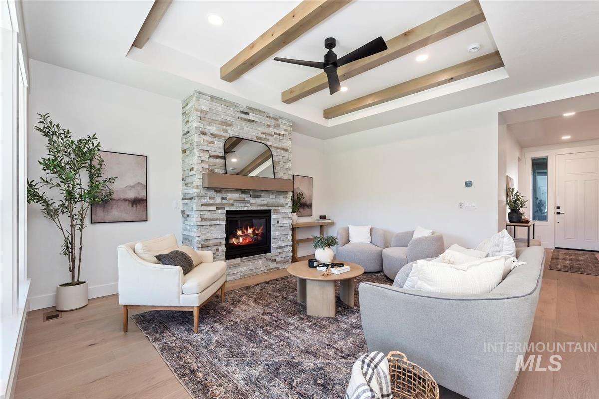 2242 East Rodeo Street Kuna, ID 83634 - Photo 5 of 37 Living room with light wood-style floors, a stone fireplace, recessed lighting, a ceiling fan, and a tray ceiling