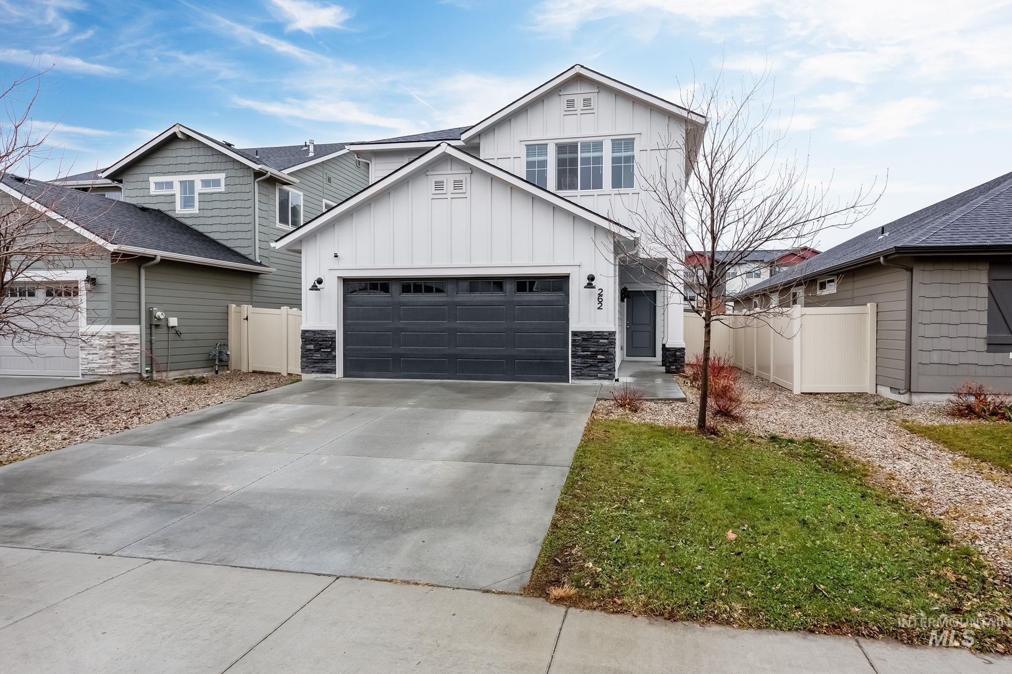 View of front of house featuring board and batten siding, concrete driveway, and stone siding