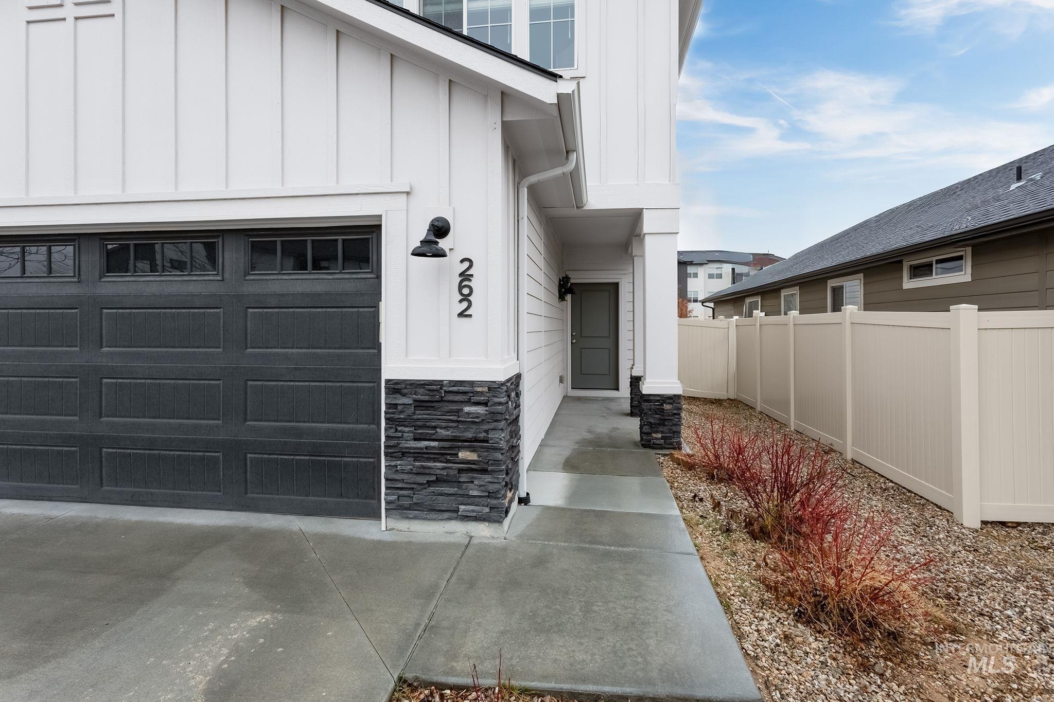 262 South Riggs Spg Avenue Meridian, ID 83642 - Photo 2 of 25 Doorway to property featuring board and batten siding, stone siding, and a garage
