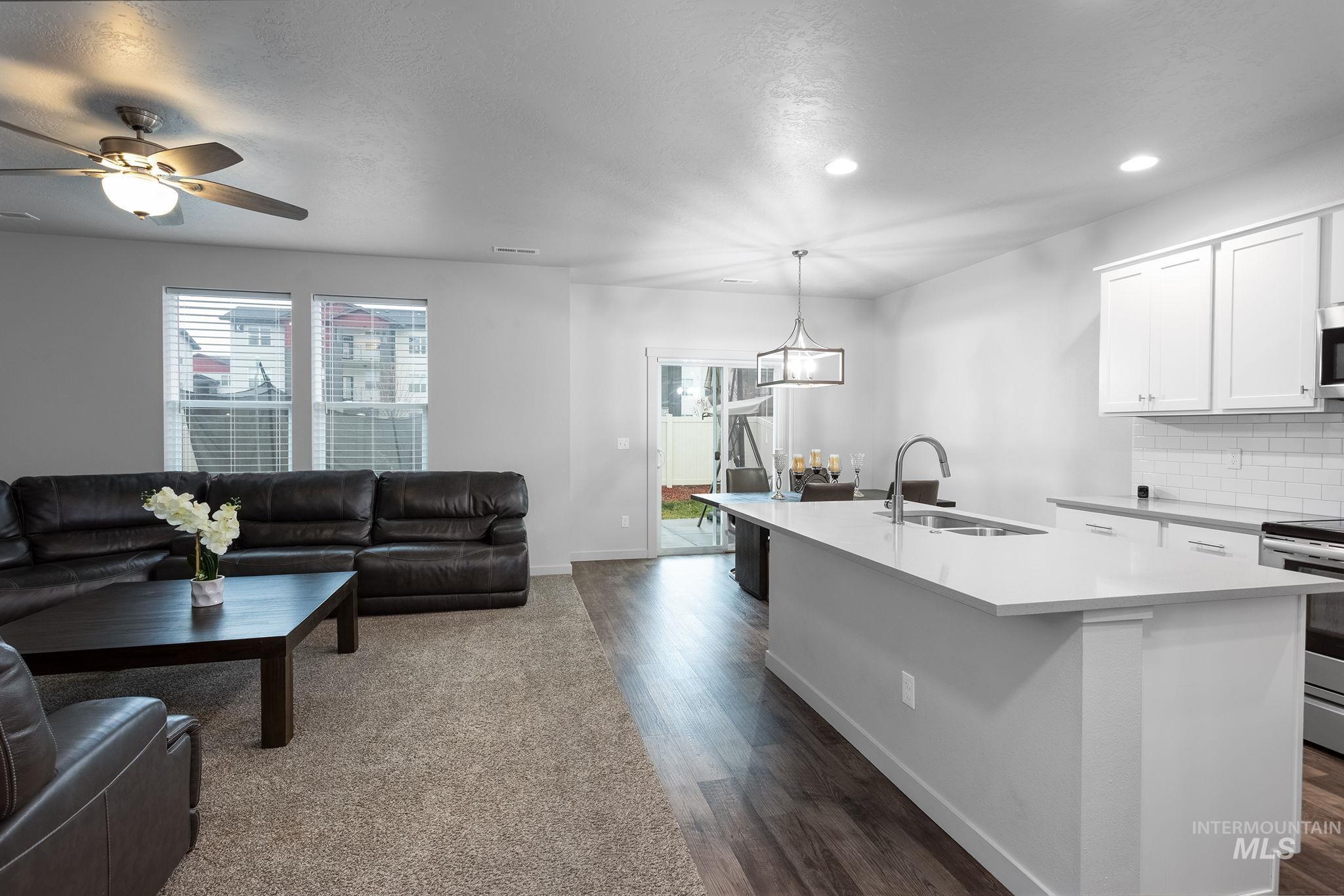262 South Riggs Spg Avenue Meridian, ID 83642 - Photo 25 of 25 Kitchen with white cabinetry, open floor plan, appliances with stainless steel finishes, backsplash, and a textured ceiling
