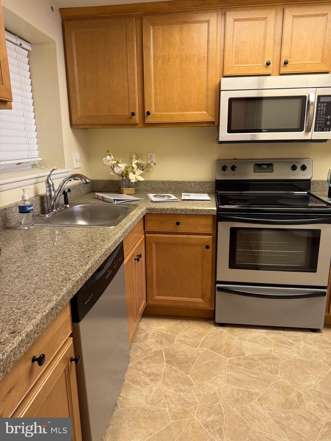 15401 Bassett Lane, Unit 452E Silver Spring, MD 20906 - Photo 14 of 31 a kitchen with stainless steel appliances granite countertop a sink stove and microwave