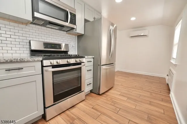 a kitchen with stainless steel appliances a stove a microwave oven cabinets and a wooden floor