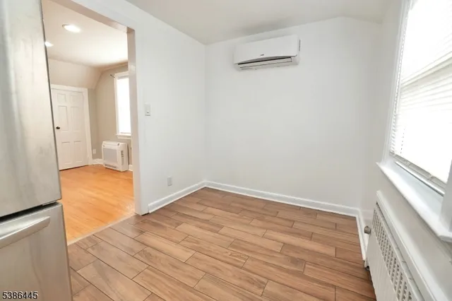 a view of empty room with wooden floor and window
