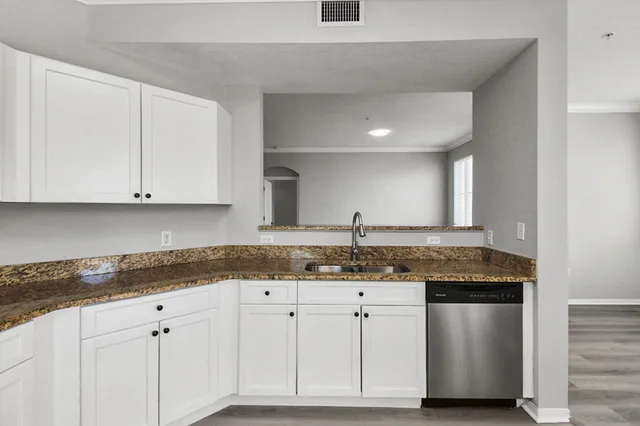 a kitchen with granite countertop white cabinets and a sink