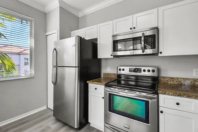 a kitchen with cabinets stainless steel appliances and wooden floor