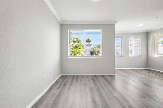 an empty room with wooden floor and windows