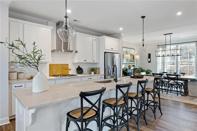 a kitchen with stainless steel appliances a table chairs refrigerator and microwave