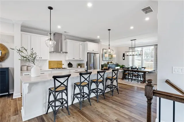 a kitchen with stainless steel appliances a dining table chairs stove and white cabinets
