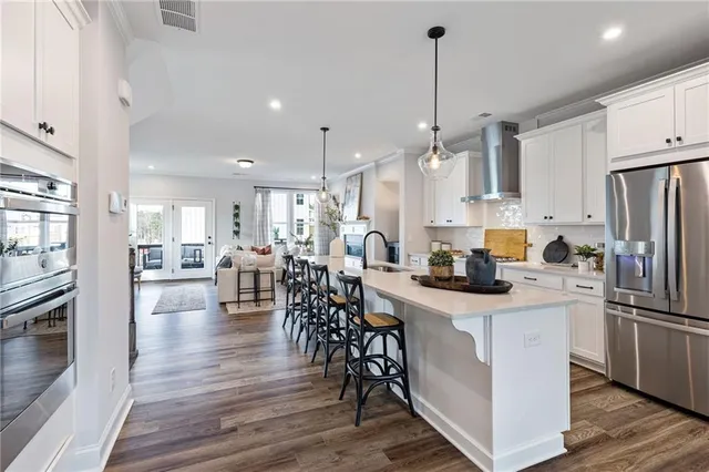 a kitchen with stainless steel appliances a dining table chairs stove and white cabinets