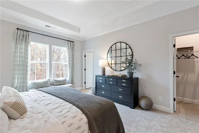 a bedroom with a bed a mirror on table and a large window