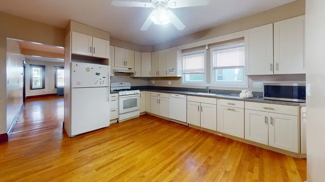 a kitchen with granite countertop white cabinets and white appliances