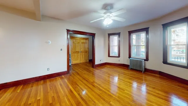 a view of empty room with wooden floor and fan