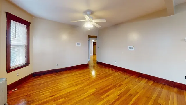 a view of an empty room with window and wooden floor