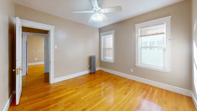 a view of an empty room with window and wooden floor