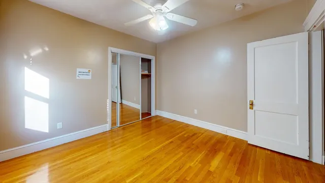 a view of empty room with wooden floor and fan