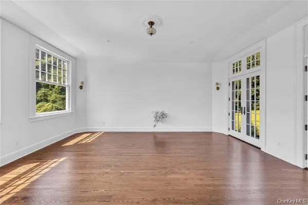 a view of an empty room with window and wooden floor