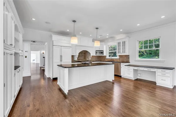 a kitchen with stainless steel appliances kitchen island wooden floors and white cabinets