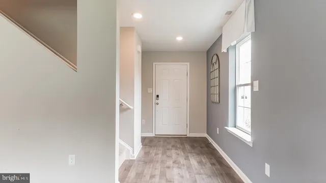 a view of hallway with window and wooden floor