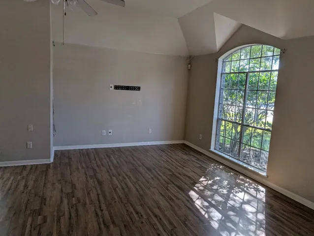 an empty room with wooden floor and windows