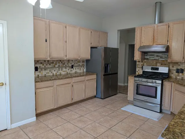a kitchen with stainless steel appliances granite countertop a refrigerator stove and sink