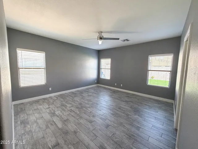 an empty room with wooden floor and windows