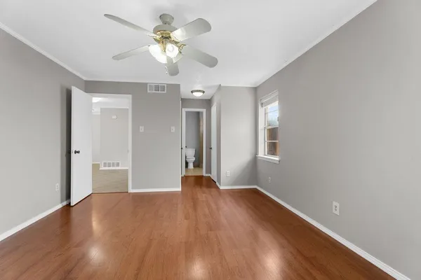 a view of an empty room with a window and wooden floor