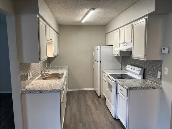 a kitchen with granite countertop a sink stove and refrigerator
