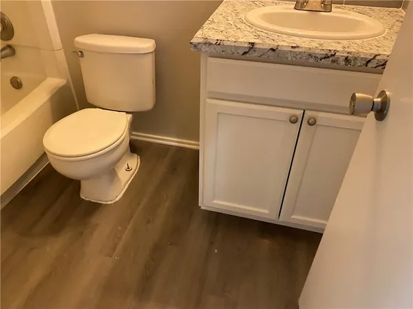 a bathroom with a granite countertop toilet and a sink