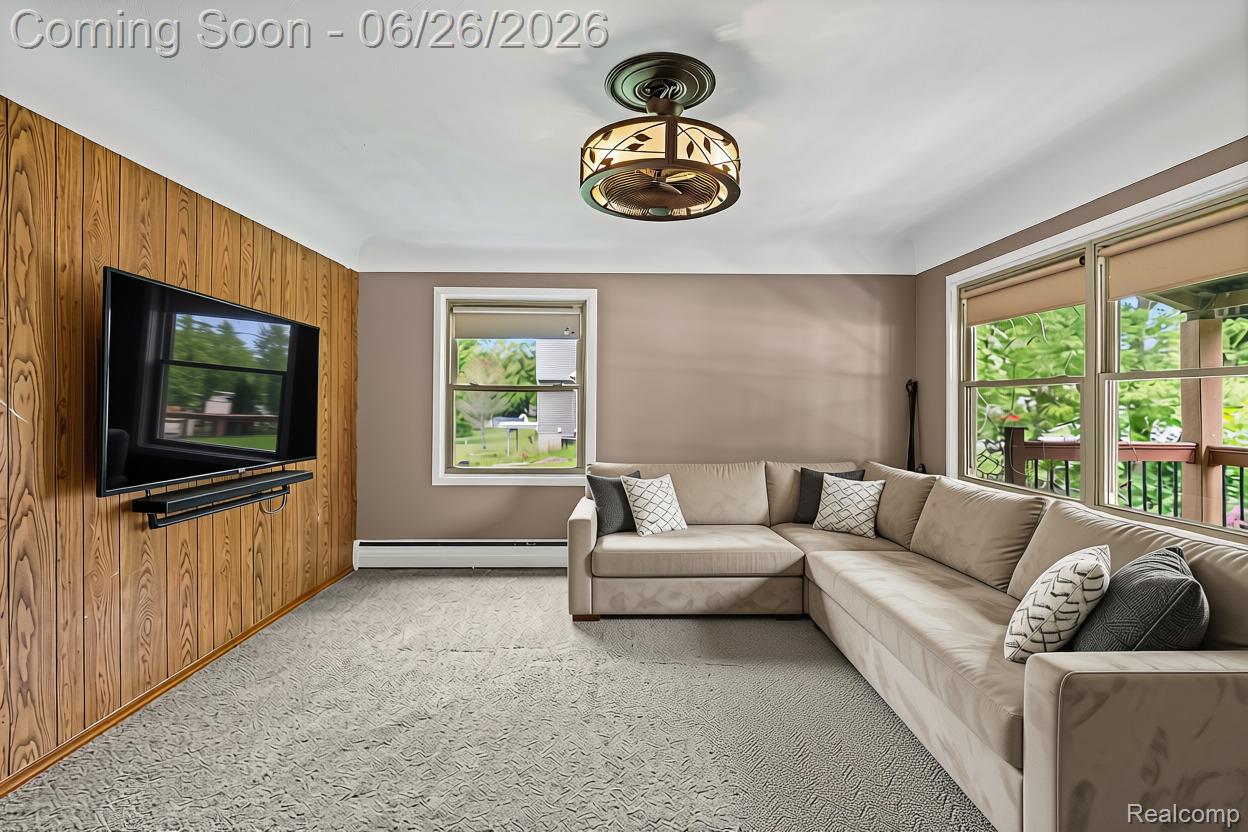 5366 East Mt Morris Road Mount Morris, MI 48458 - Photo 19 of 57 AI Edited Living space featuring wood paneling, wall-mounted television, and a decorative ceiling light fixture