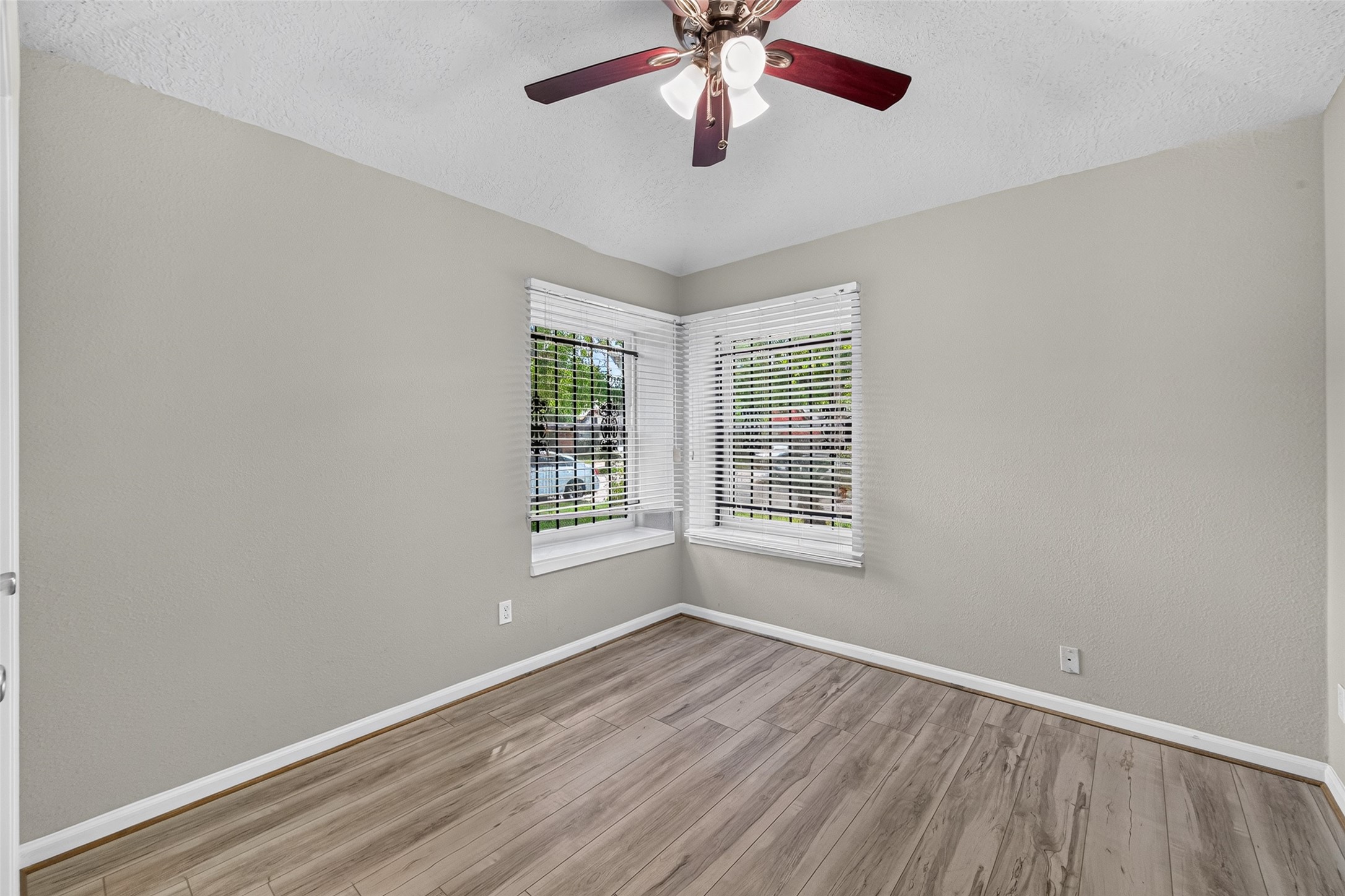 16203 Beck Ridge Drive Houston, TX 77053 - Photo 19 of 29 Bed room with large corner windows, elegant wood flooring, and a stylish ceiling fan, perfect for a cozy retreat or office space.
