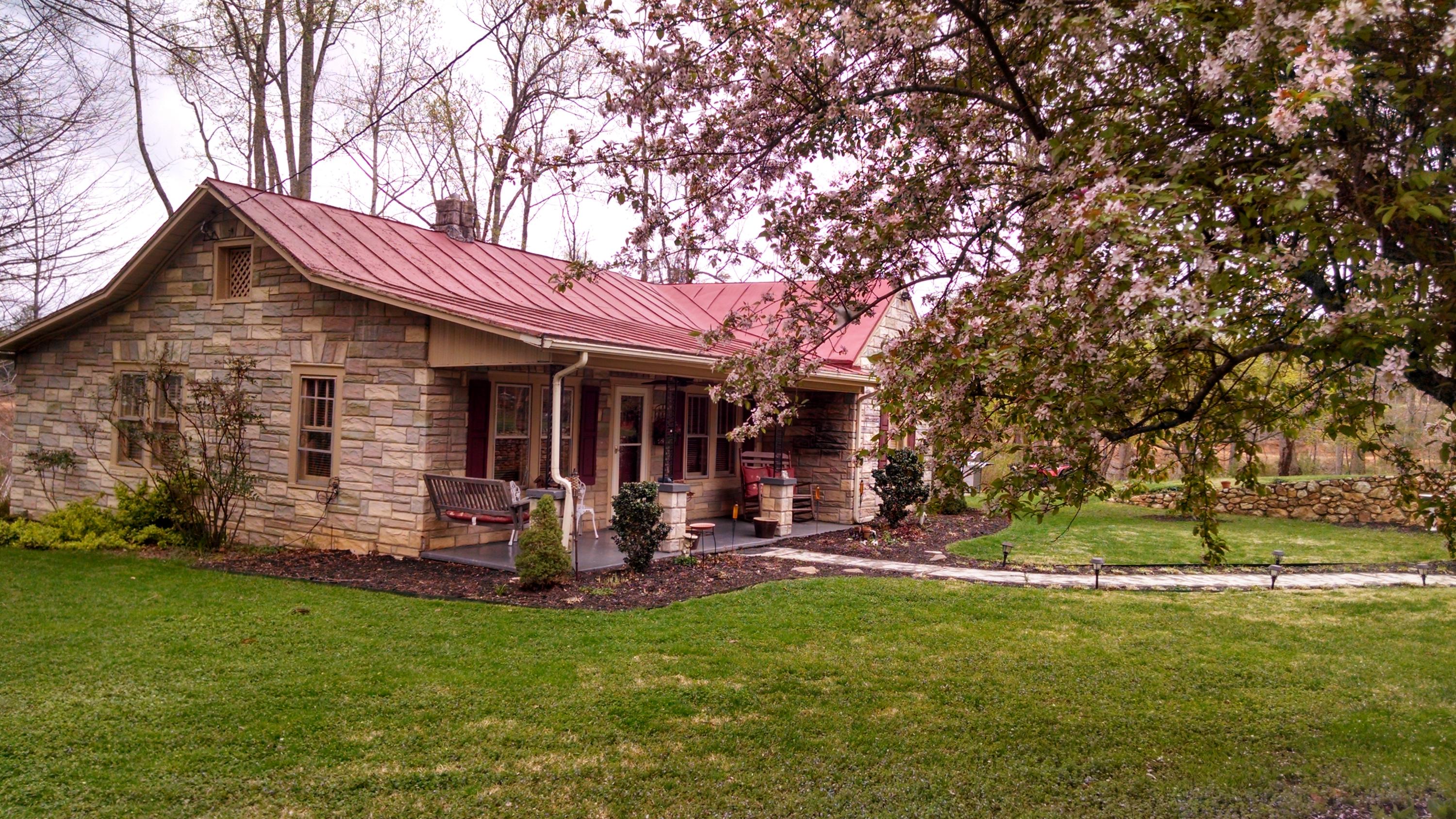 a view of a house with a yard fire pit and a large tree