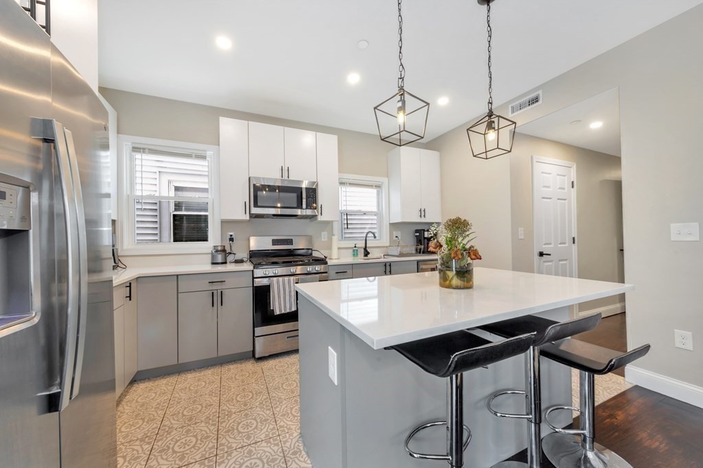 777 Columbia Road, Unit 2 Boston, MA 02125 - Photo 2 of 21 a large kitchen with kitchen island a dining table chairs stainless steel appliances and cabinets