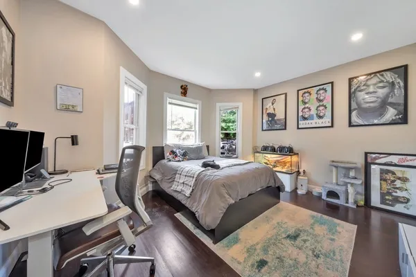 a bedroom with a bed a desk and chair with wooden floor