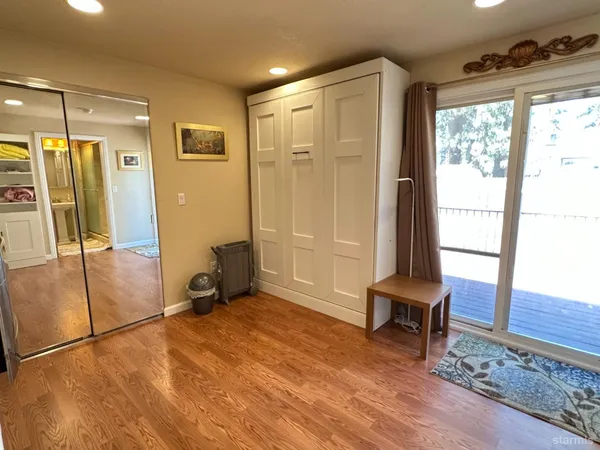 a view of a hallway with wooden floor and a bathroom