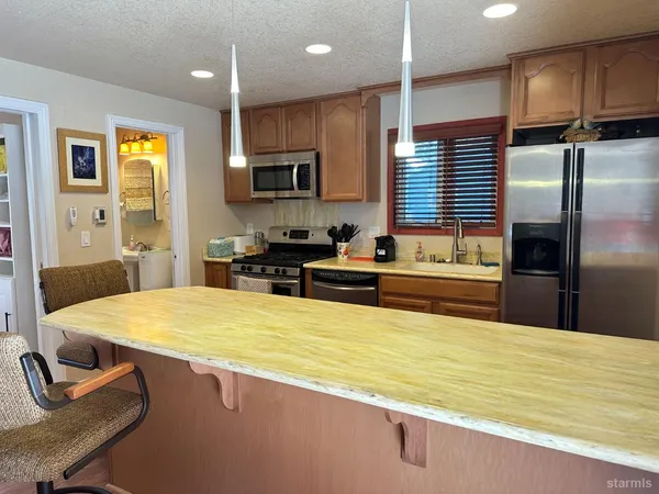 a kitchen with stainless steel appliances granite countertop a sink refrigerator stove and microwave