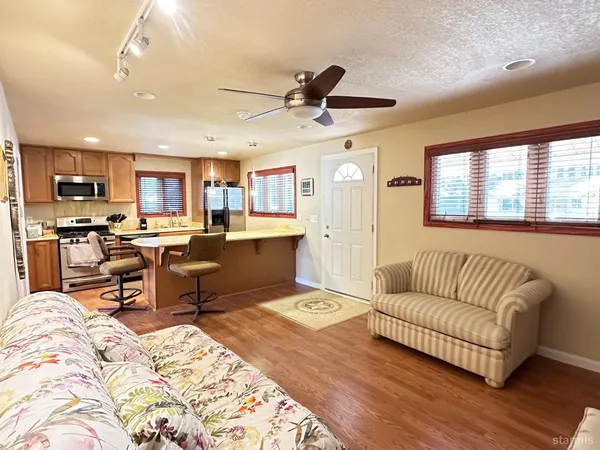 a living room with furniture kitchen and a wooden floor