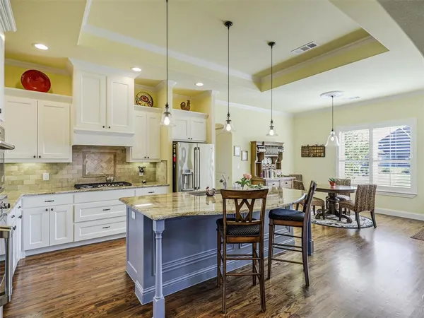a large kitchen with cabinets chairs and wooden floor