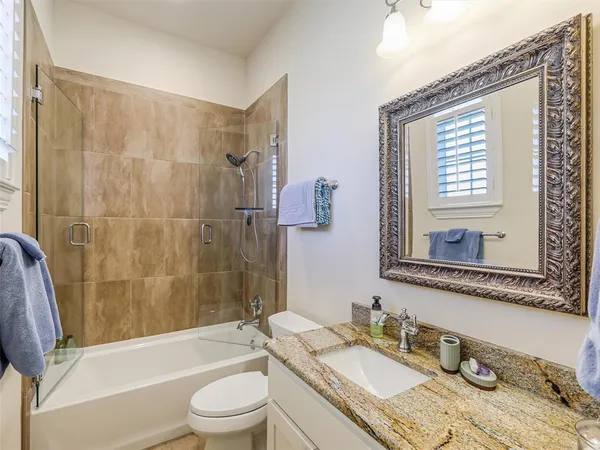 a bathroom with a granite countertop sink toilet a mirror and shower