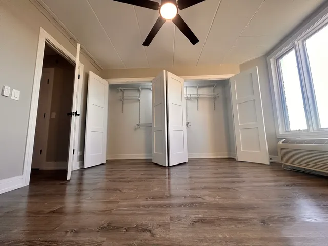 a view of empty room with wooden floor and fan